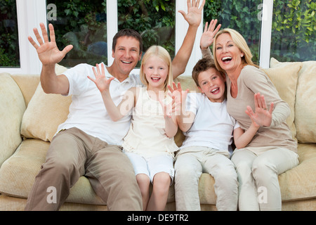 Eine attraktive glückliche Familie von Mutter, Vater, Sohn und Tochter sitzen auf einem Sofa zu Hause Spaß Stockfoto