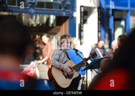 Junge Frau Straßenmusiker spielt akustischen Gitarre um die Menge in der Buchanan Street, Glasgow, Scotland, UK Stockfoto