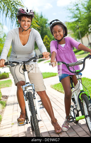 Eine glückliche afroamerikanische Frau und Kind, Mutter & Tochter, Radfahren zusammen. Stockfoto