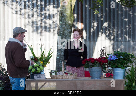 Chichester, West Sussex, UK. 14. September 2013. Beim Goodwood Revival. Goodwood-Rennstrecke, West Sussex - Samstag, den 14. September. Eine Blumenverkäuferin hinter ihrem Stall verkauft grand Prix Rosen. Bildnachweis: MeonStock/Alamy Live-Nachrichten Stockfoto