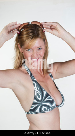 Frau trägt Bikini-Top und hält Sonnenbrillen Stockfoto