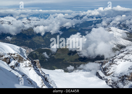 Blick hinunter auf Schnee bedeckt Berge und grüne Dörfer in der Jungfrau-Region der Schweiz. Jungfraujoch entnommen auf 3500m Stockfoto