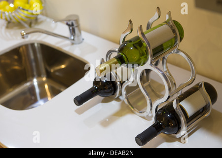 Drei Flaschen Wein mit leeren Etiketten in einem stilvollen Weinregal auf einer Küche oder Bar Theke neben einem Waschbecken Stockfoto