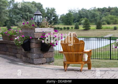 Person in einem Gartenstuhl mit dem Rücken zur Kamera mit Blick auf Landschaft und einem kleinen See entspannen Stockfoto