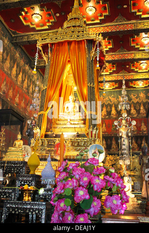 Ein Altar mit einem goldenen Buddha und Lotus Blüten in einem buddhistischen Tempel Bangkok. Stockfoto