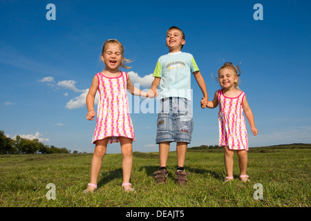 Zwillingsmädchen, 3 Jahre, und ihr Bruder, 7 Jahre, im freien Stockfoto