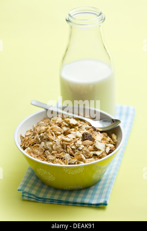 Müsli in Keramikschale und Milch auf farbigen Hintergrund Stockfoto