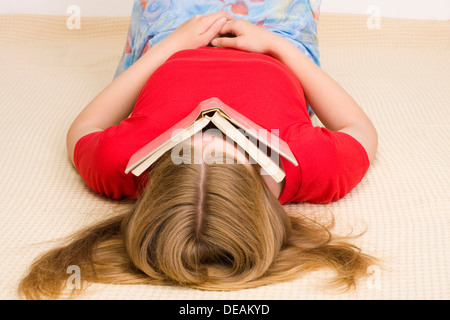 Mädchen, 17 Jahre, auf dem Boden bedeckte ihr Gesicht mit einem Buch Stockfoto