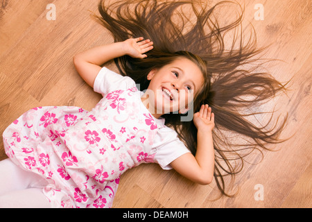 Mädchen, 4 Jahre, auf dem Boden liegend, lachen Stockfoto