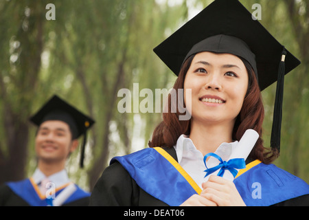 Zwei junge Hochschulabsolventinnen und-Absolventen hält Diplome, Frau vor Stockfoto
