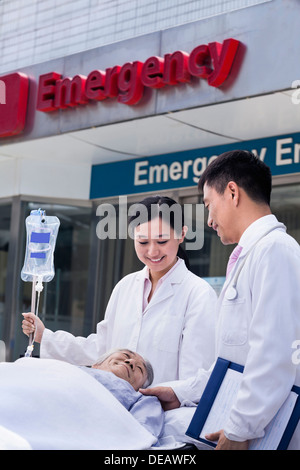 Zwei Ärzte, die bei einem Patienten auf einer Bahre vor der Notaufnahme Machenschaften Stockfoto