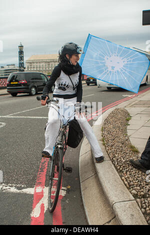 London, UK. 15. September 2013. Mädchen mit Eisbär Flagge am Fahrrad auf Lambeth Bridge vor Greenpeace Veranstaltung, weltweit größte Eisbär Marionette Parade, Shell Oil London HQ zu nehmen.  Bildnachweis: Martyn Wheatley/Alamy Live News Stockfoto