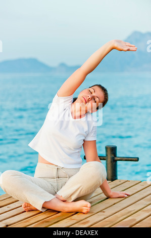 junge Frau, die engagiert in Pilates am Meer Stockfoto