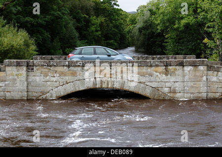 Lochlip Road, Lochwinnoch, Renfrewshire, Schottland, Großbritannien, Sonntag, 15. September 2013. Ein Auto überquert die alte Steinbrücke, nachdem heftiger Regen hohe Flussniveaus und schnell fließendes Wasser auf dem Fluss Calder verursachte Stockfoto