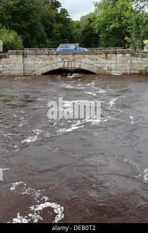 Lochlip Road, Lochwinnoch, Renfrewshire, Schottland, Großbritannien, Sonntag, 15. September 2013. Ein Auto überquert die alte Steinbrücke, nachdem heftiger Regen hohe Flussniveaus und schnell fließendes Wasser auf dem Fluss Calder verursachte Stockfoto