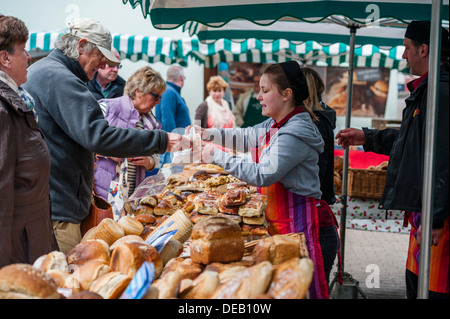 Eine junge Frau verkaufen frisches Brot auf Bauernmarkt Haverfordwest, Pembrokeshire. Wales UK Stockfoto