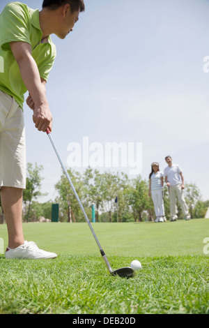 Junger Mann, Kollision mit einem Ball auf dem Golfplatz, Mann und Frau im Hintergrund Stockfoto