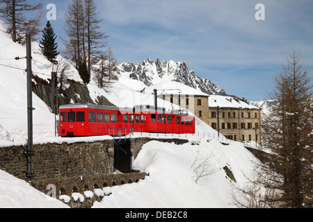 Ein roter Berg Zug im Schnee bedeckt Berge. Stockfoto