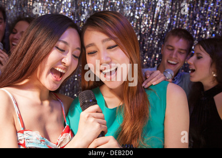 Gruppe von Freunden in ein Mikrofon Karaoke singen Stockfoto