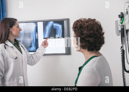 Junge Ärztin, die auf eine Röntgenaufnahme mit einem Patienten sitzen Stockfoto