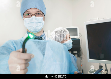 Porträt des jungen Chirurgen halten ein medizinisches Instrument in Richtung der Kamera, leicht glänzend Stockfoto