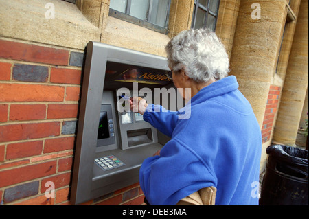 Eine weibliche Senioren eine ATM Karte einfügen Stockfoto