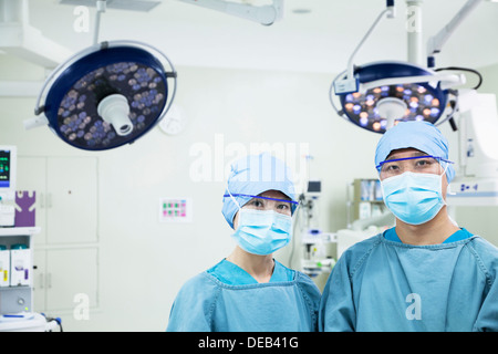 Porträt von zwei Chirurgen tragen Mundschutz im OP-Saal, Blick in die Kamera Stockfoto
