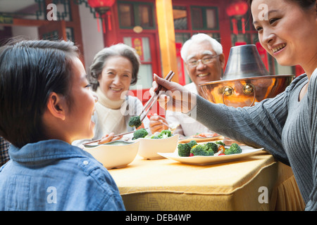 Mutter Fütterung Tochter Brokkoli während einer Mahlzeit Stockfoto