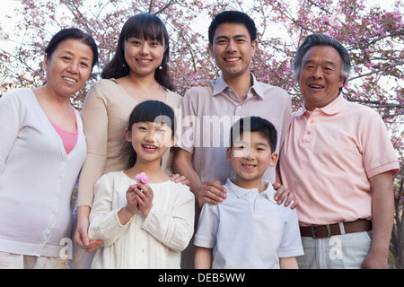 Porträt eines Lächeln mehr-Generationen-Familie unter den Kirschbäumen und genießen den Park im Frühling Stockfoto