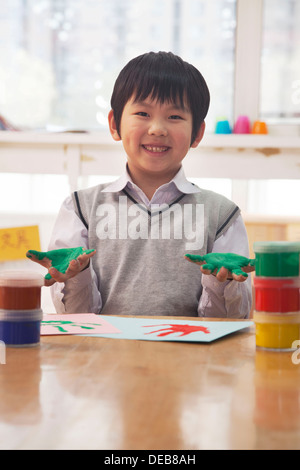 Porträt des Lächelns Schuljunge Fingermalerei im Kunstunterricht, Beijing Stockfoto