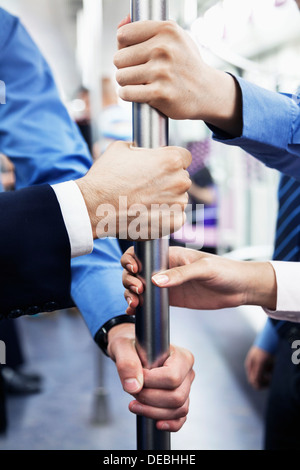 Nahaufnahme von vier Geschäftsleuten Hände halten die Pole in der u-Bahn Stockfoto