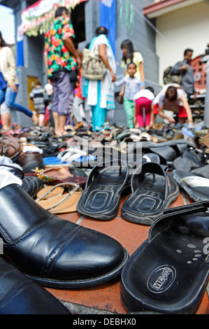 Paar Schuhe und andere Schuhe links auf dem Bürgersteig vor der Sri-Mariamman-Tempel in Singapur. Stockfoto