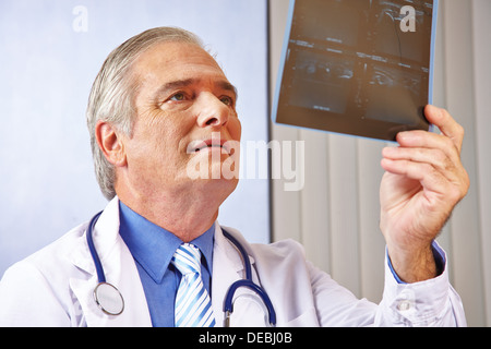 Arzt mit Blick auf Röntgen-Bild in seinem Krankenhaus-Büro Stockfoto