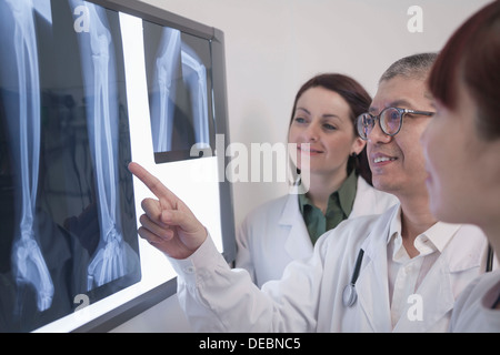 Drei lächelnden Ärzte Röntgenstrahlen von menschlichen Knochen zu betrachten, ist ein Arzt zeigen. Stockfoto