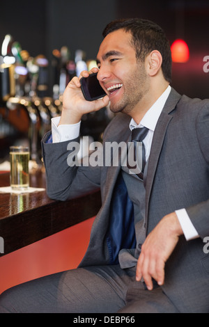 Fröhliche Geschäftsmann auf dem Handy einen Drink Stockfoto