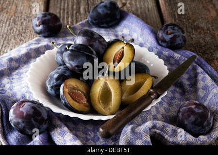 Frische Pflaumen (Prunus Domestica) auf Teller legen, mit einem Messer und einem Küchentuch Stockfoto