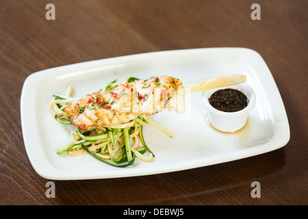 Asiatisch inspirierte Fischgericht mit Nudeln und Julienne-Gemüse Stockfoto