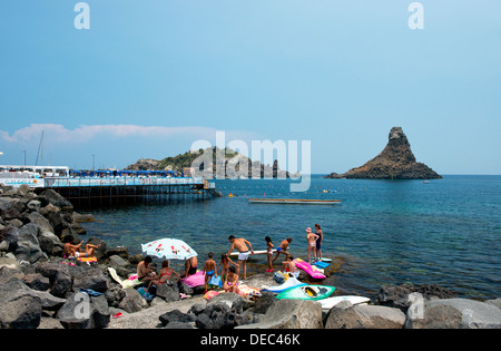 Sonnenanbeter auf Felsen in Aci Trezza mit Blick auf den Zyklopen-Inseln in der Nähe von Taormina, Sizilien, Italien Stockfoto