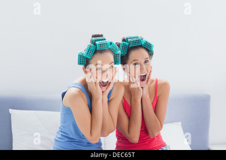 Freunde mit Lockenwickler auf sitzen im Bett Stockfoto