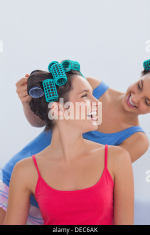 Mädchen tragen Lockenwickler sitzen im Bett Stockfoto