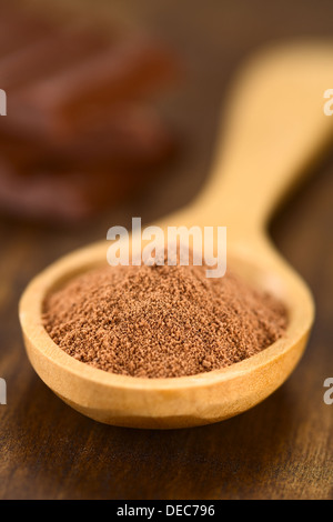 Kakaopulver auf Holzlöffel mit Schokoladenstückchen in den Rücken (sehr flache Schärfentiefe, Fokus ein Drittel in den Kakao) Stockfoto