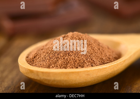 Kakaopulver auf Holzlöffel mit Schokoladenstückchen in den Rücken (sehr flache Schärfentiefe, Fokus ein Drittel in den Kakao) Stockfoto