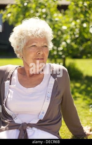 Porträt des entspannten alte Dame sitzt auf Rasen suchen - im freien Stockfoto