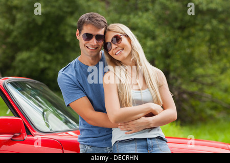 Fröhliches paar umarmt und lehnte sich gegen cabriolet Stockfoto