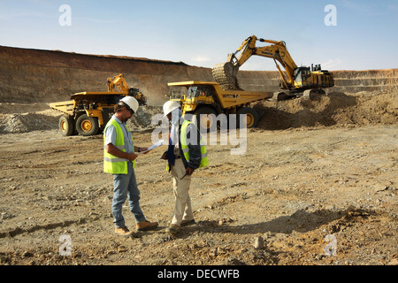 Vorgesetzten anweist Trainee im Tagebau Oberfläche Goldmine Grube mit Bagger und Haul Truck hinter, Mauretanien, NW-Afrika Stockfoto