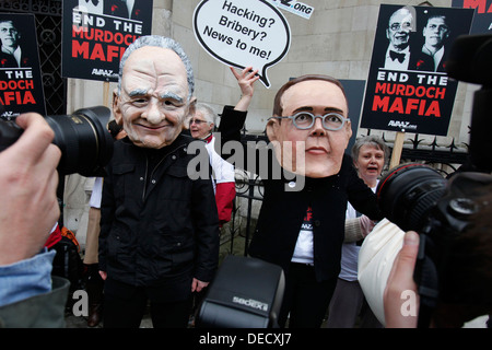 Demonstranten mit Masken von James Murdoch (L) und sein Vater Rupert (R) zeigen außerhalb der Leveson-Anfrage Stockfoto