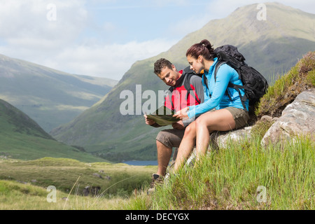 Paar eine Pause nach dem Wandern bergauf und Lesung Karte Stockfoto