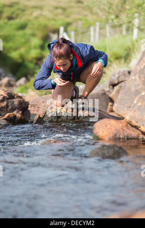 Wanderer, die Biegung um einen Drink zu nehmen, aus dem stream Stockfoto