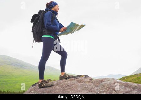 Frau steht auf einem Felsen Holding Karte Stockfoto