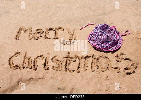 Frohe Weihnachten, geschrieben in den Sand mit Baby Mütze Stockfoto